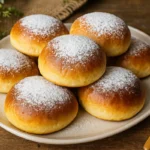 Nadýchané domáce buchty s čokoládou na tanieri, posypané cukrom.