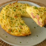Hotová cestovinová omeleta so slaninou a parmezánom na tanieri.