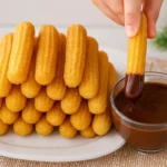 Domáce churros obalené v škoricovom cukre s miskou čokolády.
