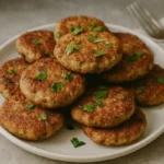 Hromada zlatistých chlebových fašírok so slaninou na tanieri, ozdobené čerstvou petržlenovou vňaťou.